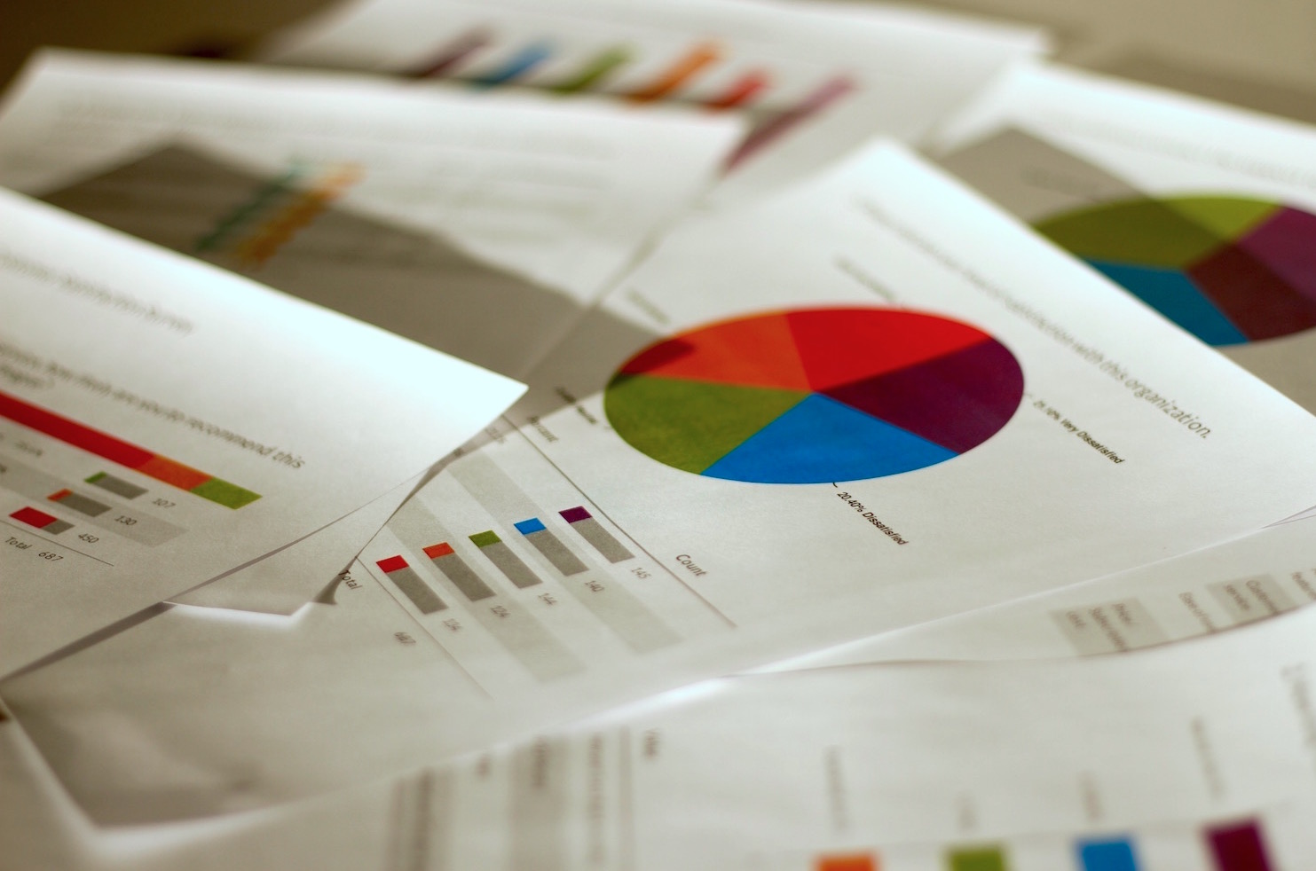 pie graph and bar charts printed on paper strewn on a desk