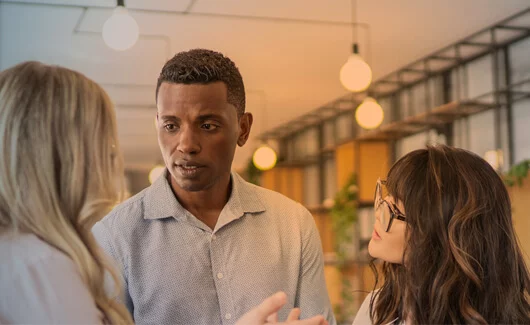 Three people in a tight circle talking intently