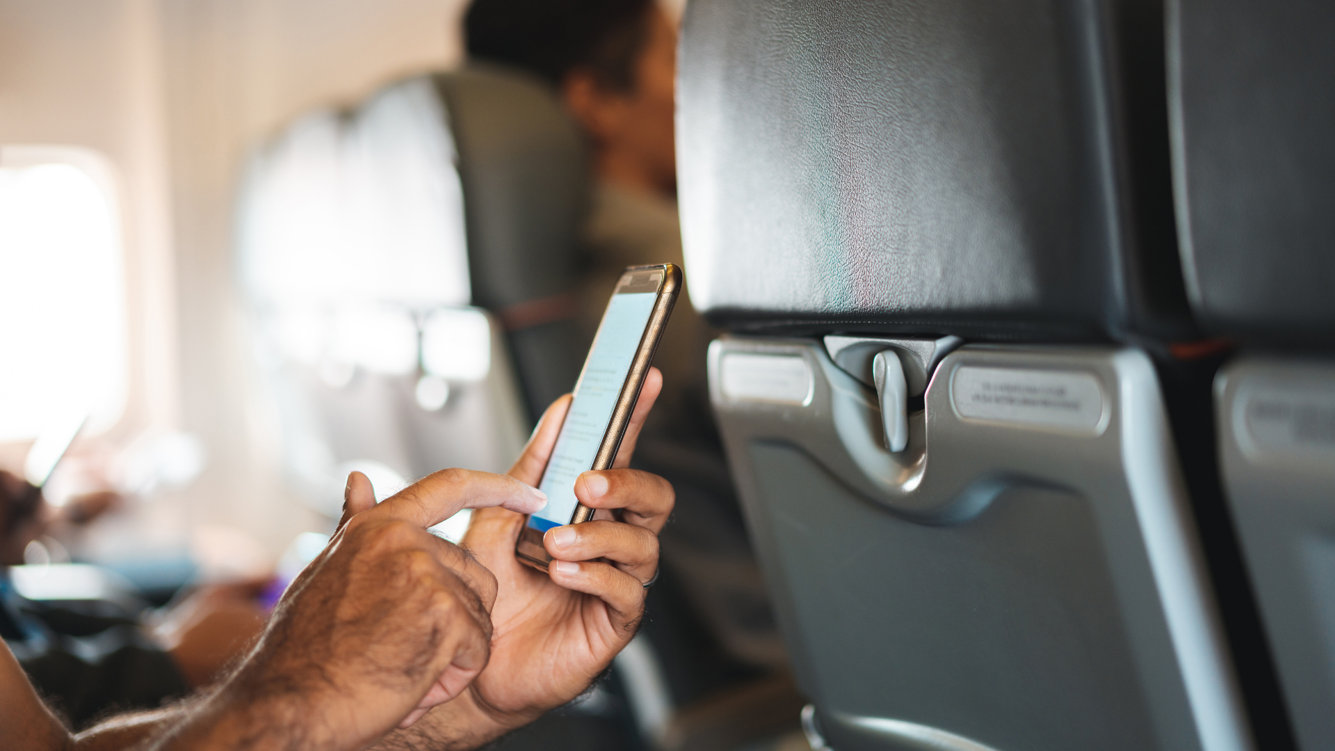 Person holding a mobile device on an airplane using a travel app