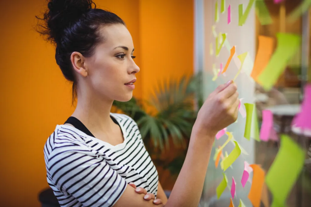 Woman putting up sticky notes on a glass board