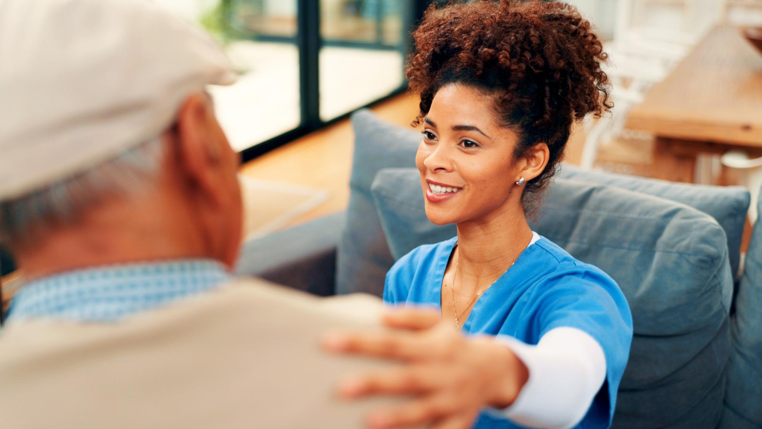 Home healthcare nurse comforting a senior patient during an in-home care visit.